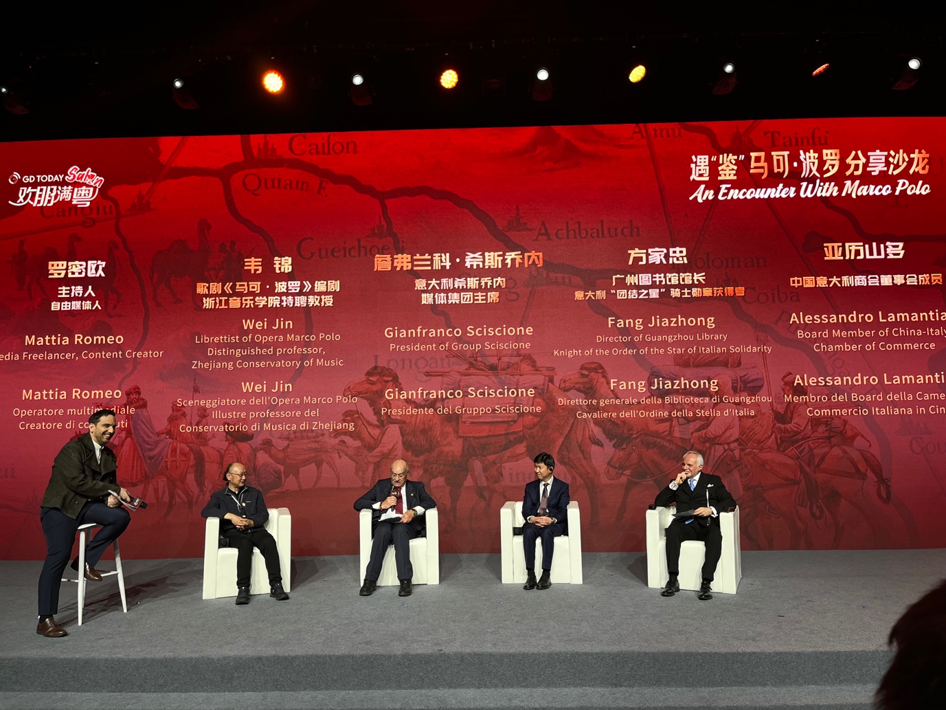 A group of men sitting on a stage
Description automatically generated